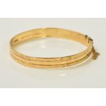 A 9CT GOLD BANGLE, of faceted design with diamond cut swag detail to the edges, with 9ct hallmark