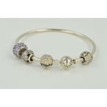 A PANDORA CHARM BANGLE, the circular bangle with Pandora clasp, one non Pandora purple paste