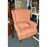 A REPRODUCTION PINK STRIPPED UPHOLSTERED WING BACK ARMCHAIR, on brass casters