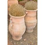 A PAIR OF LARGE TERRACOTTA AMPHORA SHAPED GARDEN URNS with double hooped handles, height 73cm x