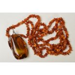 AN AMBER NECKLACE AND PENDANT, the pendant designed as a large polished piece of amber within an