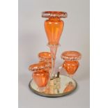 A LATE VICTORIAN ORANGE AND CLEAR GLASS EPERGINE, central invested baluster vase surrounded by three