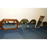 AN EDWARDIAN OAK BEVELLED EDGE WALL MIRROR, together with three circular wall mirrors and another