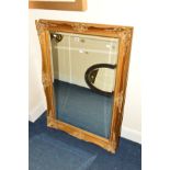 A REPRODUCTION FOLIATE GILT FRAMED BEVELLED EDGE WALL MIRROR, approximately 107cm x 76cm (s.d.)