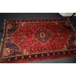 A 20TH CENTURY WOOLLEN KUBA RUG, red and blue ground of a geometric design, approximately 253cm x