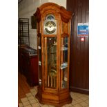 HOWARD MILLER, USA, a golden oak chiming long case clock of a canted form, the arched dial with