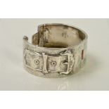 AN EARLY 20TH CENTURY SILVER HINGED BANGLE, with buckle design and engraved ivy leaf detail, with