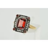 A GARNET AND DIAMOND RING, designed as a rectangular garnet within a brilliant cut diamond