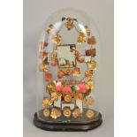 A VICTORIAN GLASS DOME, on an ebonised base, containing a gilt metal arrangement with bird and