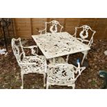 A WHITE PAINTED GARDEN SET with foliate decoration, comprising a square table and four armchairs (