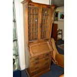 AN ARTS AND CRAFTS OAK BUREAU BOOKCASE, the upper section with overhanging cornice supported on