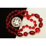 A RED PASTIC BEAD NECKLACE AND A SCOTTISH BROOCH, the necklace with spherical and barrel shape