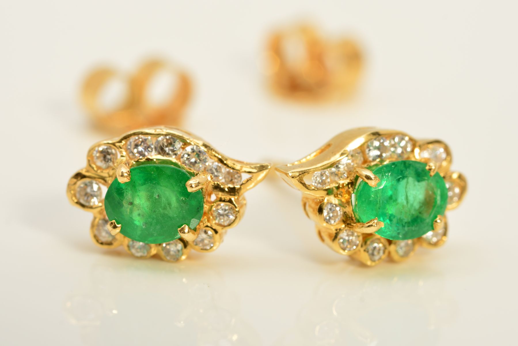 A MODERN PAIR OF EMERALD AND DIAMOND OVAL CLUSTER EARRINGS, emeralds measuring approximately 5mm x