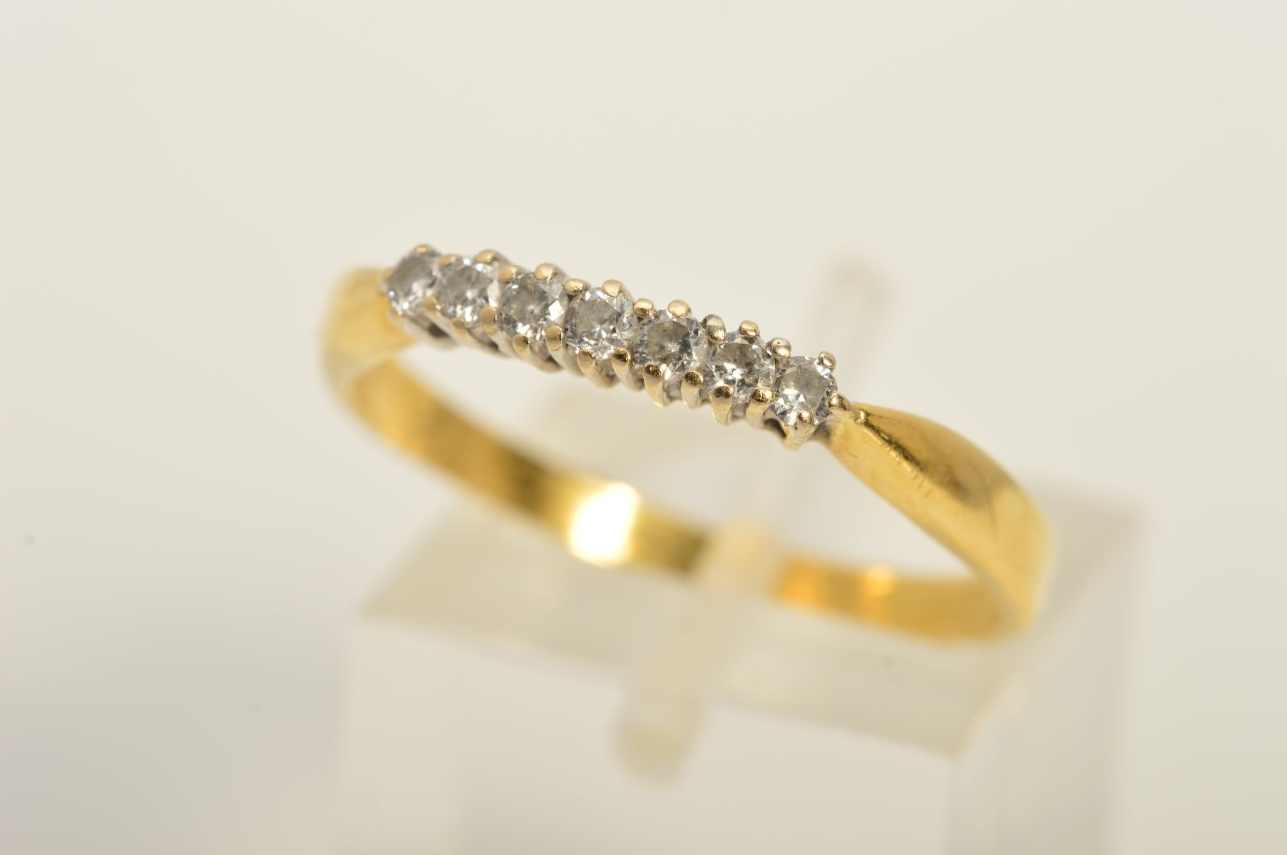 A GOLD SEVEN STONE DIAMOND RING, designed as a row of seven brilliant cut diamonds within claw
