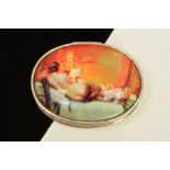 AN OVAL HINGED PILL BOX, the lid with a transfer depicting the back of a lady laid reading a book,