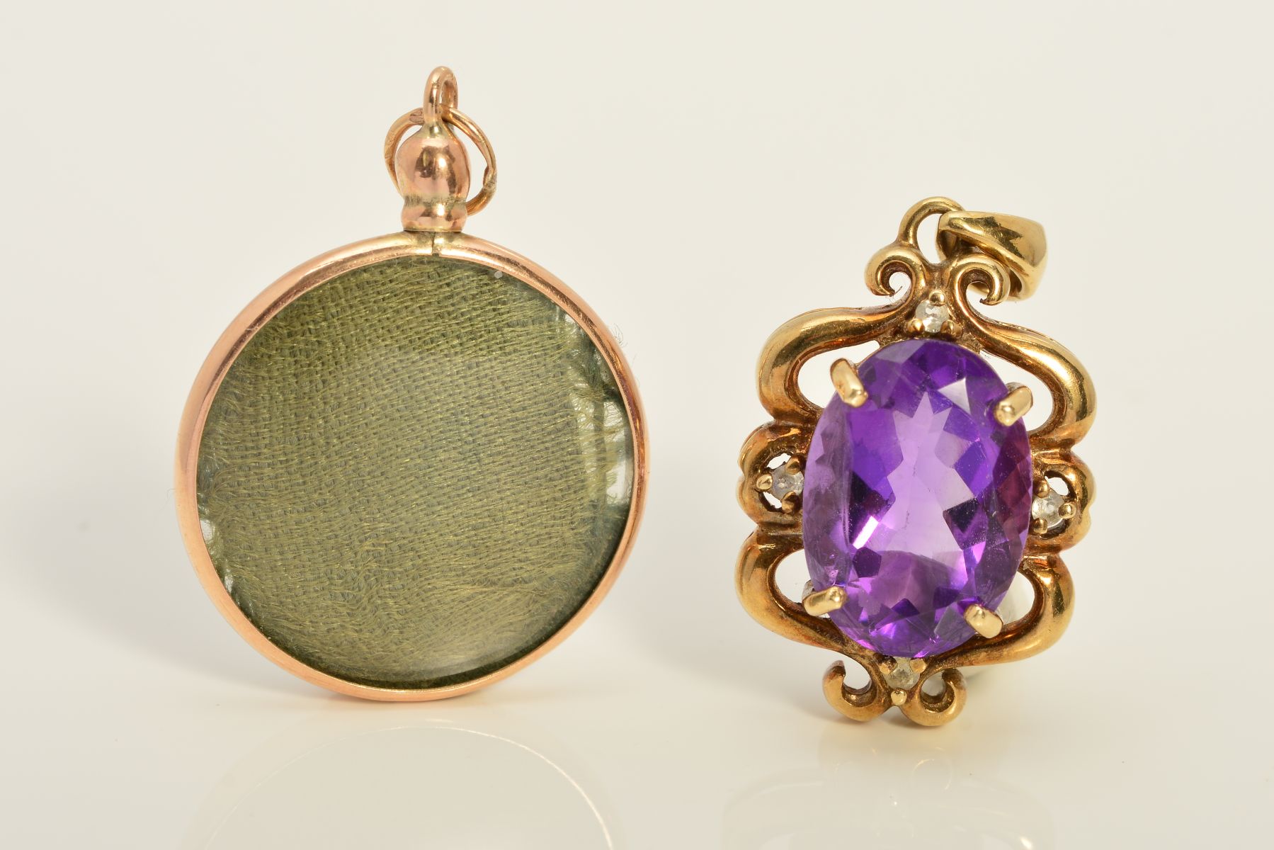 TWO 9CT GOLD PENDANTS, the first designed as an oval amethyst within an openwork scrolling surround,