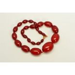 A RED PLASTIC BEAD NECKLACE, designed as graduated barrel shape beads measuring 11mm to 36mm to