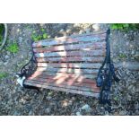 A TEAK SLATTED AND WROUGHT IRON GARDEN BENCH with lions head