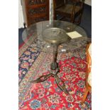 AN INDUSTRIAL CIRCULAR GLASS TOPPED TABLE, on a base formed from engine parts, diameter 64cm x