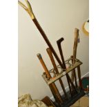 A BRASS AND CAST IRON STICK STAND, together with five walking sticks, one of which has an antler