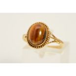 A 9CT GOLD TIGER'S EYE RING, designed as an oval tiger's eye cabochon within a rope twist surround