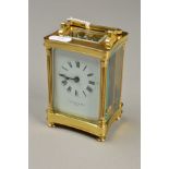 A BRASS CARRIAGE CLOCK, the white face with black Roman numerals, glass sides and back, stamped