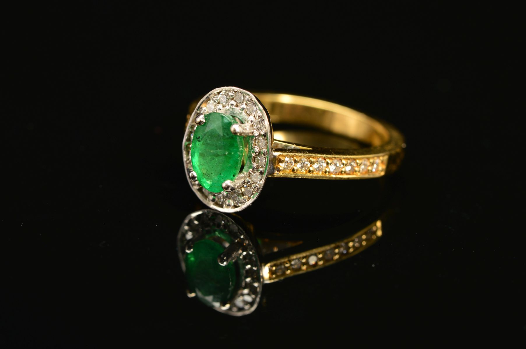 A MODERN 18CT GOLD EMERALD AND DIAMOND HALO CLUSTER STYLE RING, with diamond set shoulders,