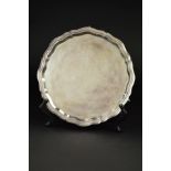 AN ELIZABETH II SILVER SALVER, of wavy circular form, on three cabriole legs with scrolled feet,