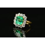 AN IMPRESSIVE 18CT GOLD EMERALD AND DIAMOND CLUSTER RING, centring on an emerald cut emerald
