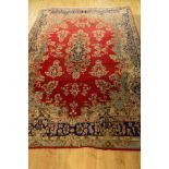 A LATE 19TH / EARLY 20TH CENTURY WOOLLEN CARPET, red ground with a deep border of foliate motifs and