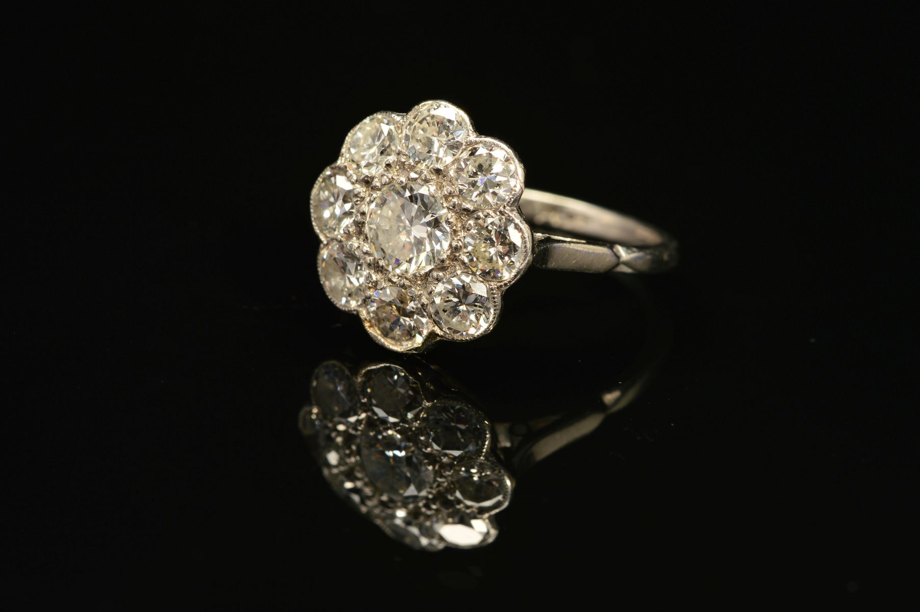 A DIAMOND CLUSTER RING, the central brilliant cut diamond within a surround of eight brilliant cut