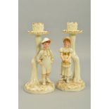 A PAIR OF ROYAL WORCESTER KATE GREENWAY STYLE FIGURAL CANDLESTICKS, modelled by James Hadley,