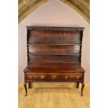 A GEORGE III OAK AND MAHOGANY BANDED DRESSER, the back with moulded cornice above a wavy frieze,