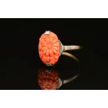 AN EARLY 20TH CENTURY CARVED CORAL RING, an oval floral panel measuring approximately 15mm x 10mm,