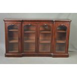 A VICTORIAN WALNUT BOOKCASE OF INVERTED BREAKFRONT FORM, rounded corners to the frieze above four