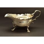 A GEORGE II SILVER SAUCEBOAT, wavy rim, 'S' scroll handle, on three cabriole legs, shell knees and