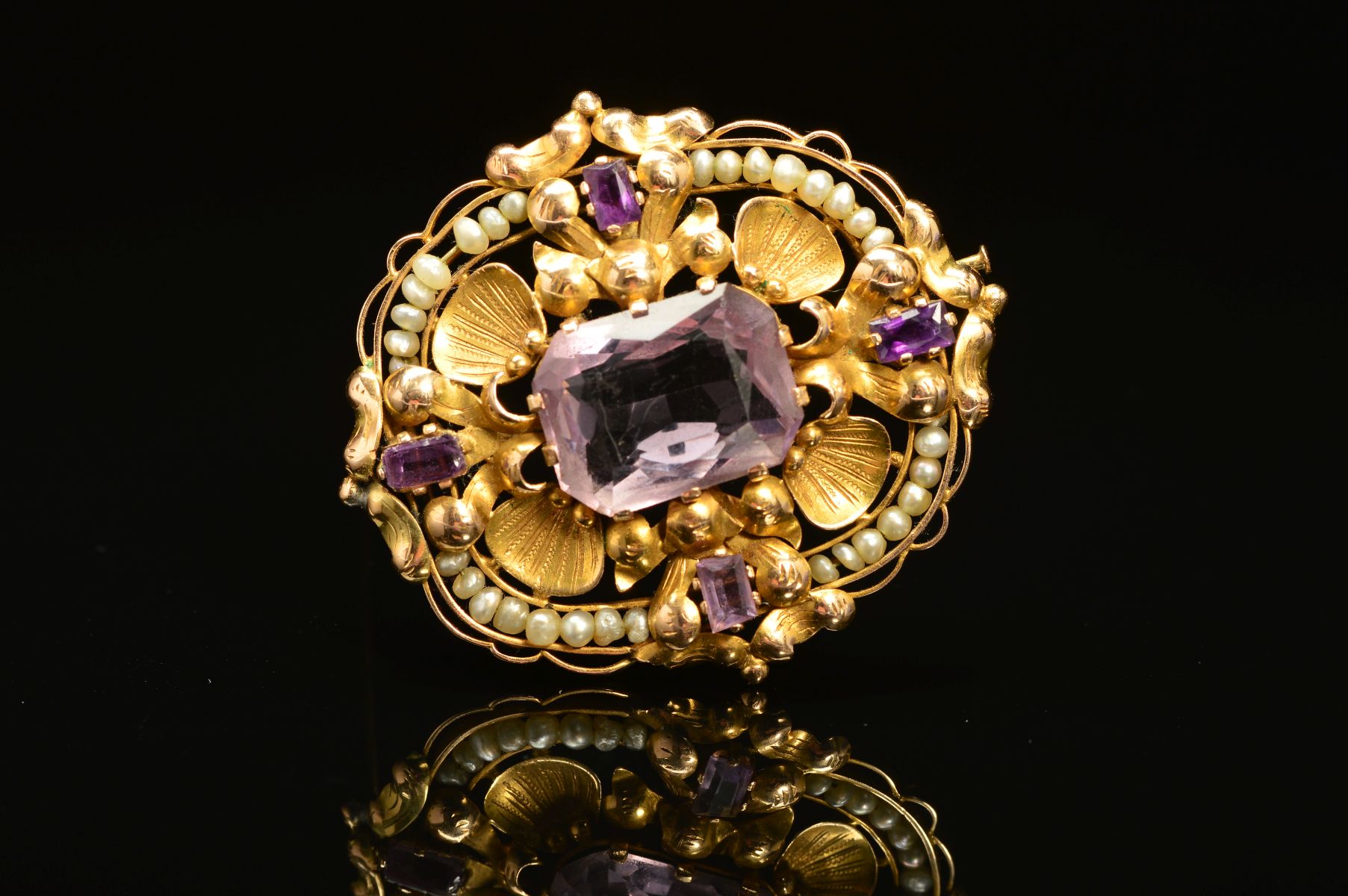 A GOLD AMETHYST AND SEED PEARL BROOCH, the central rectangular amethyst, surrounded by shell and