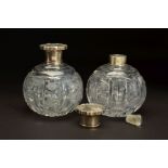 A PAIR OF EARLY 20TH CENTURY SPHERICAL GLASS SCENT BOTTLES, with white metal pull off covers stamped