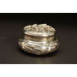 A LATE 19TH CENTURY CONTINENTAL SILVER TRINKET BOX, of circular form, the hinged cover repousse