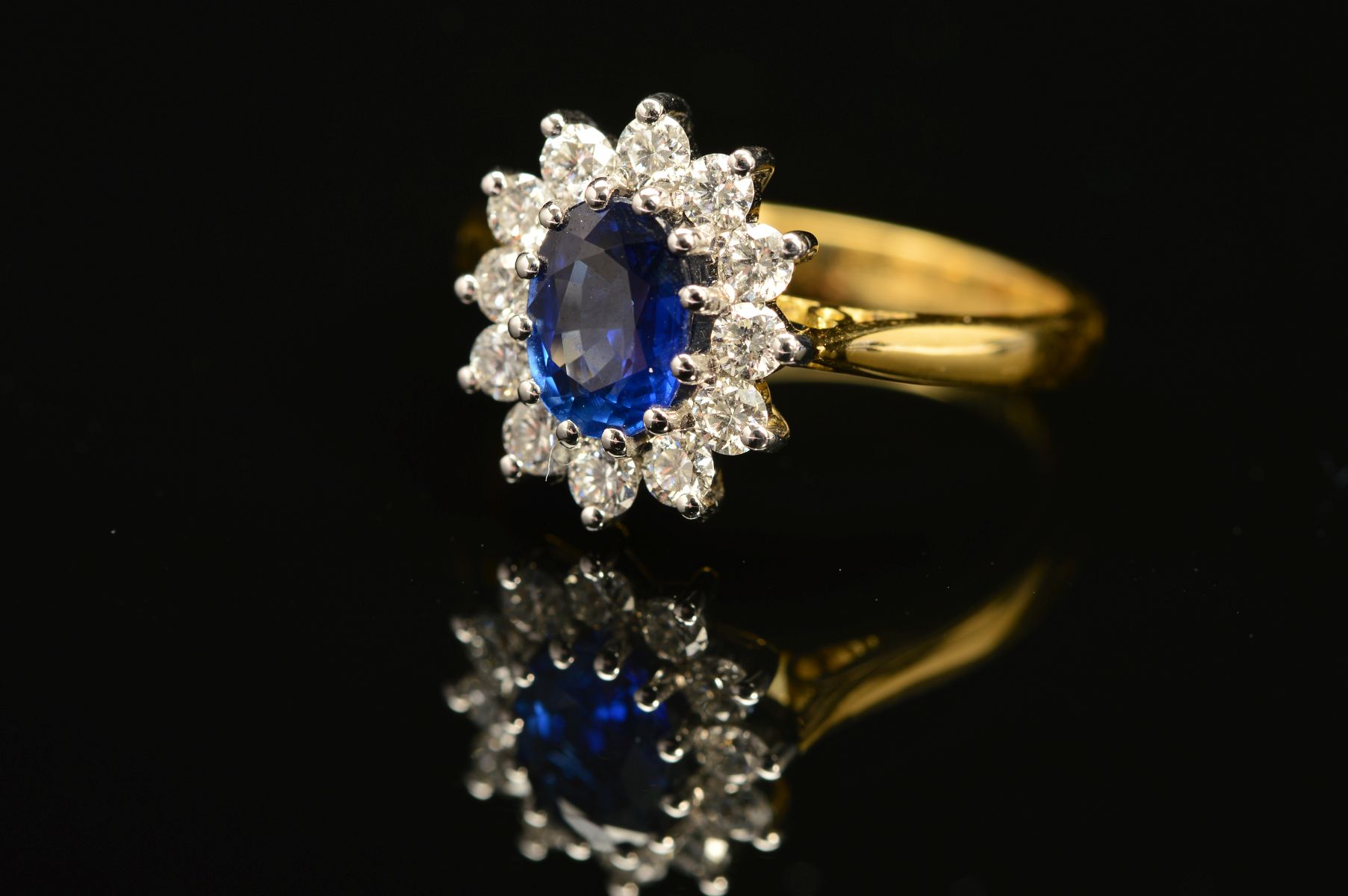 A MODERN 18CT GOLD SAPPHIRE AND DIAMOND OVAL CLUSTER RING, oval blue sapphire measuring