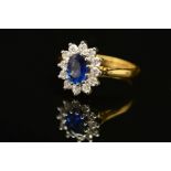 A MODERN 18CT GOLD SAPPHIRE AND DIAMOND OVAL CLUSTER RING, oval blue sapphire measuring