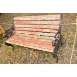 A TEAK SLATTED AND WROUGHT IRON GARDEN BENCH with lions head