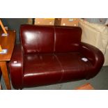 A BURGUNDY LEATHER TWO SEATER SETTEE