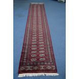 A TEKKE STYLE RED GROUND CARPET RUNNER, multi strap, 428cm x 81cm