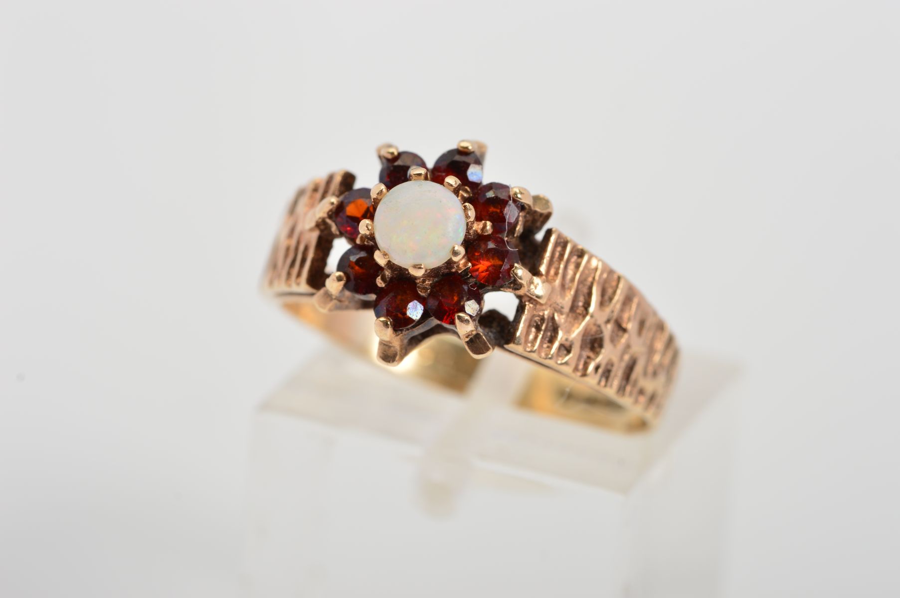 A 9CT GOLD OPAL AND GARNET CLUSTER RING, designed as a central circular opal cabochon within a