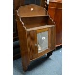 AN OAK MIRRORED SINGLE DOOR HANGING CUPBOARD