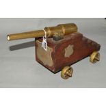 A LATE VICTORIAN BRASS AND WOODEN MODEL DESK CANNON, with shield shaped mounts, overall length 38cm