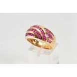 A 9CT GOLD RUBY DRESS RING, the wide tapered band channel set with curved and graduated rows of