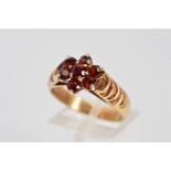 A 9CT GOLD GARNET CLUSTER RING designed as a floral cluster of seven circular garnets to the