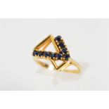 A 9CT GOLD ASYMETRICAL SAPPHIRE DRESS RING designed as two vari-sized triangles partly edged with